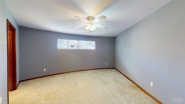 empty room with baseboards, a ceiling fan, and light colored carpet