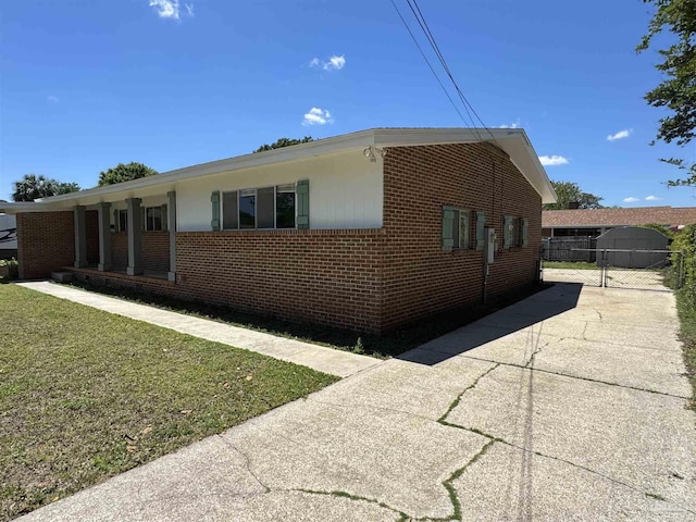 view of side of home with a lawn, brick siding, fence, and a gate