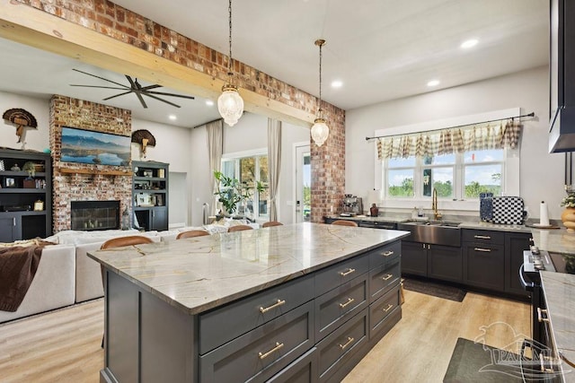 7664 Buffalo Ridge Rd, Pace, FL 32571 - kitchen featuring a kitchen island, light wood finished floors, light stone countertops, a brick fireplace, and recessed lighting