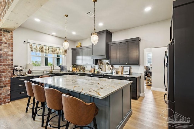 7664 Buffalo Ridge Rd, Pace, FL 32571 - kitchen with a kitchen island, light stone countertops, a breakfast bar area, light wood-type flooring, and custom range hood