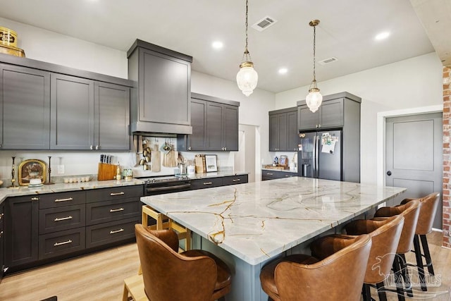 7664 Buffalo Ridge Rd, Pace, FL 32571 - kitchen featuring stainless steel refrigerator with ice dispenser, light stone counters, light wood finished floors, and recessed lighting