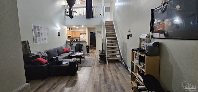 living room with a towering ceiling and wood-type flooring