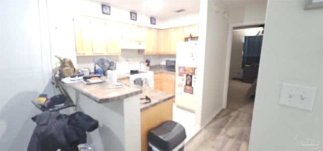 kitchen featuring a breakfast bar, exhaust hood, kitchen peninsula, light wood-type flooring, and range