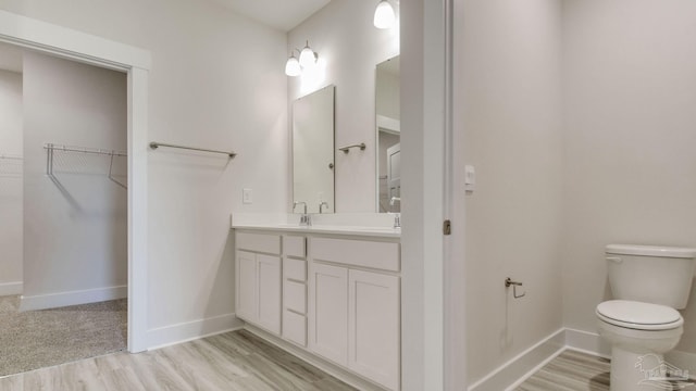 1674 Amaya Ln, Gulf Breeze, FL 32563 - bathroom featuring toilet, vanity, baseboards, wood finished floors, and a spacious closet