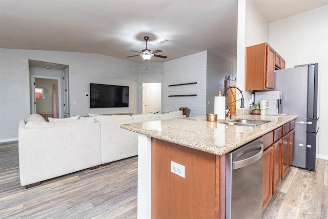 kitchen with sink, light hardwood / wood-style flooring, ceiling fan, appliances with stainless steel finishes, and light stone counters