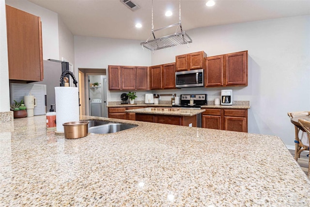 kitchen featuring sink, a center island, light stone counters, and stainless steel appliances