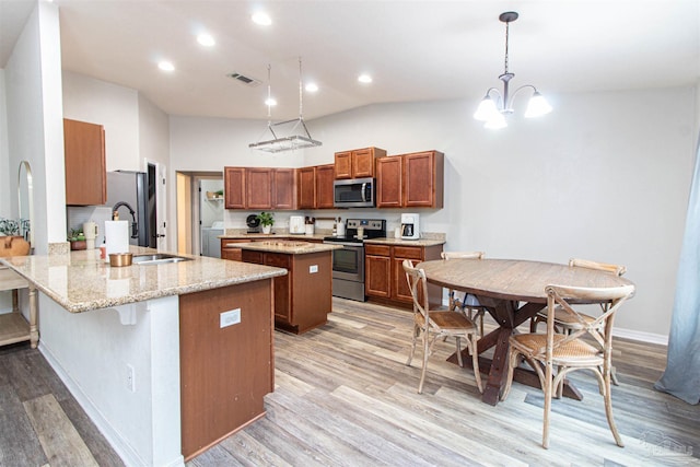 kitchen with kitchen peninsula, light stone countertops, stainless steel appliances, a chandelier, and hanging light fixtures