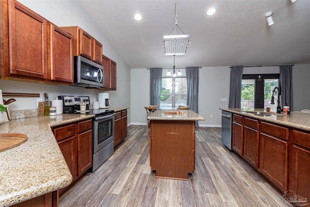 kitchen with a center island, an inviting chandelier, sink, decorative light fixtures, and stainless steel appliances