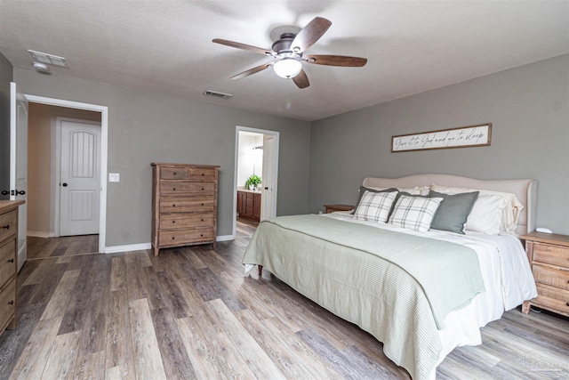 bedroom with hardwood / wood-style flooring, ceiling fan, a textured ceiling, and connected bathroom