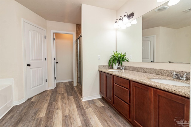 bathroom with hardwood / wood-style floors, vanity, and shower with separate bathtub