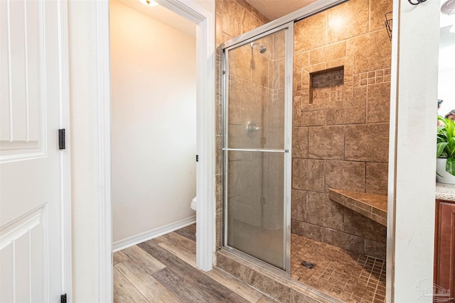 bathroom with hardwood / wood-style floors, toilet, and a shower with shower door