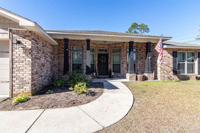 view of exterior entry featuring a lawn, a porch, and a garage