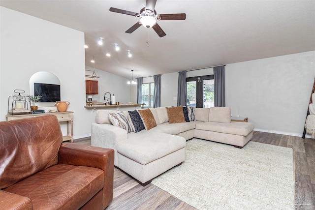 living room with ceiling fan with notable chandelier, light hardwood / wood-style floors, lofted ceiling, and french doors