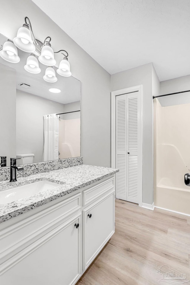 9001 Thompson Dr, Pensacola, FL 32534 - bathroom featuring wood finished floors, vanity, shower / bath combo with shower curtain, baseboards, and a closet