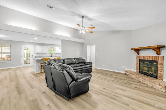 9001 Thompson Dr, Pensacola, FL 32534 - living room with a fireplace, light wood-style flooring, a ceiling fan, lofted ceiling, and a textured ceiling