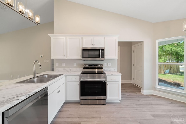 kitchen with a sink, stainless steel appliances, white cabinets, lofted ceiling, and a chandelier