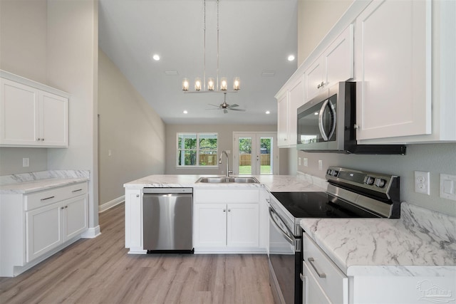 kitchen featuring a peninsula, light wood-style flooring, a sink, stainless steel appliances, and white cabinets