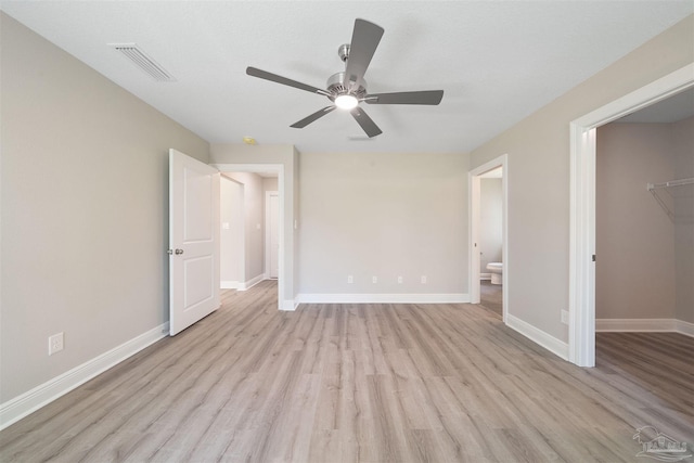 unfurnished bedroom featuring light wood-type flooring, visible vents, baseboards, ceiling fan, and a spacious closet