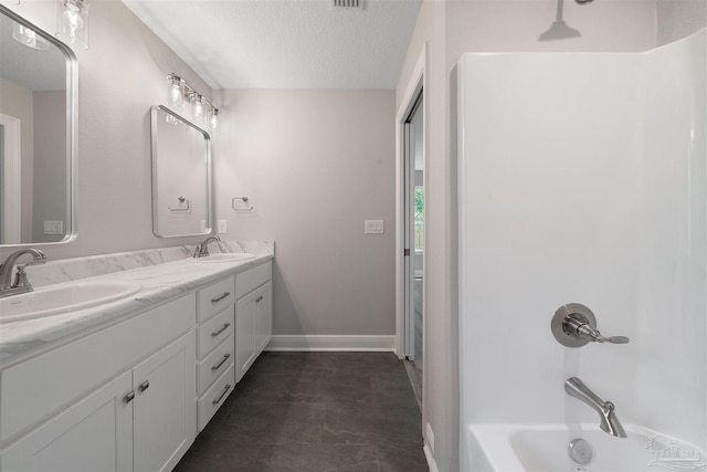bathroom with double vanity, a textured ceiling, bathing tub / shower combination, and a sink