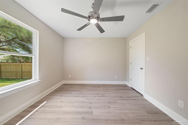 spare room featuring baseboards, visible vents, light wood finished floors, and ceiling fan