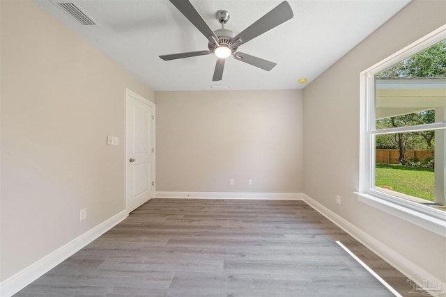 empty room featuring visible vents, plenty of natural light, light wood-style flooring, and baseboards