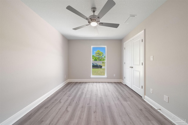 unfurnished bedroom featuring a ceiling fan, baseboards, visible vents, light wood-style flooring, and a textured ceiling