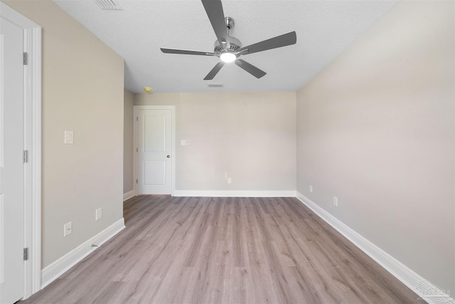 empty room featuring visible vents, ceiling fan, baseboards, light wood-type flooring, and a textured ceiling