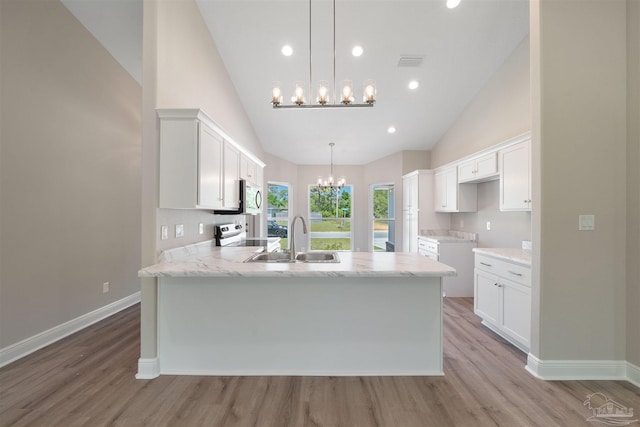 kitchen featuring visible vents, a peninsula, an inviting chandelier, white cabinets, and a sink