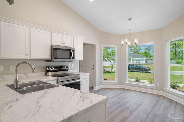 kitchen with light stone countertops, a sink, stainless steel appliances, vaulted ceiling, and white cabinetry