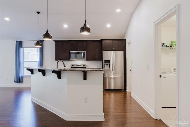 kitchen with decorative light fixtures, a kitchen island with sink, stainless steel appliances, and a breakfast bar