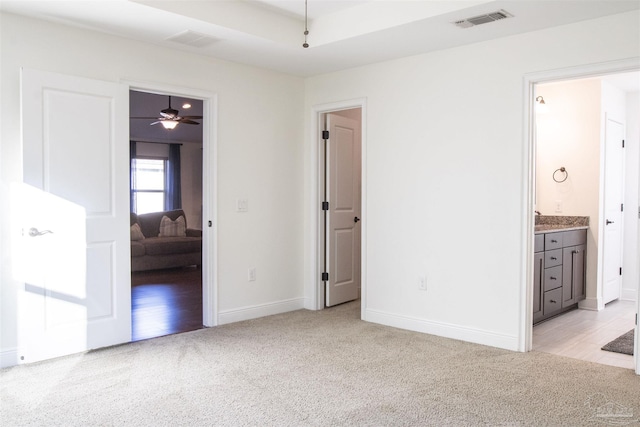 unfurnished bedroom featuring connected bathroom and light colored carpet