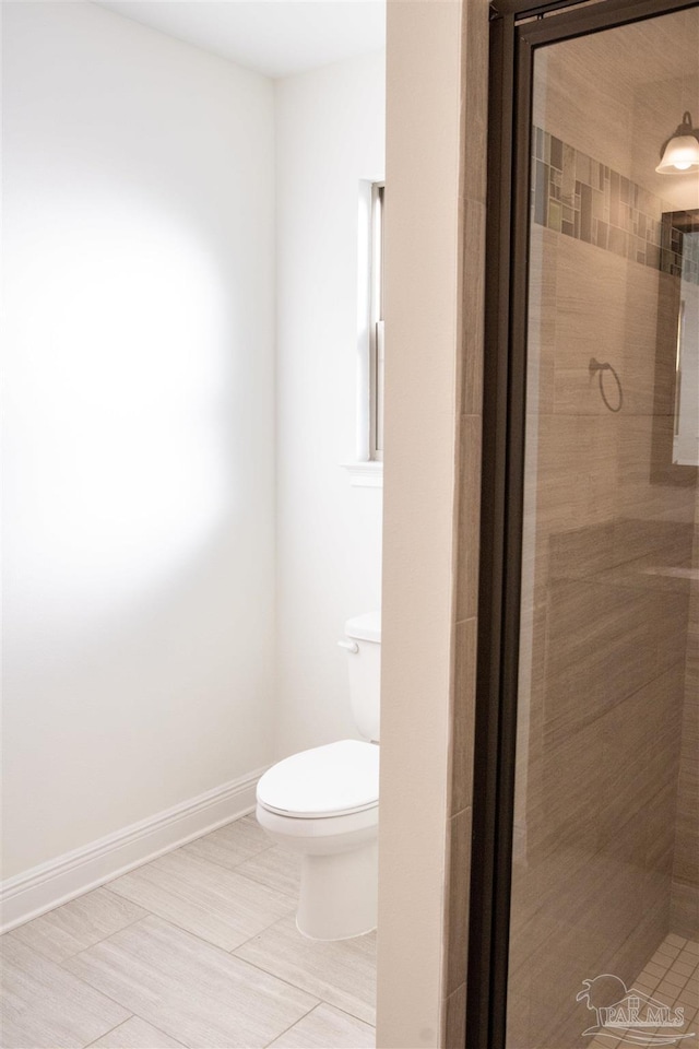 bathroom featuring a shower with shower door and toilet