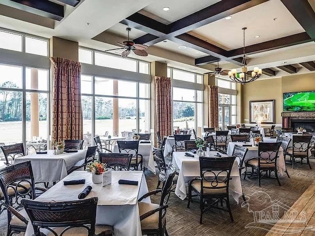 dining room featuring coffered ceiling, a healthy amount of sunlight, beam ceiling, ceiling fan with notable chandelier, and a high ceiling