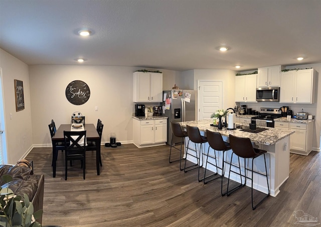 4422 Tiger Oak Ct, Pace, FL 32571 - kitchen featuring appliances with stainless steel finishes, a breakfast bar area, white cabinets, dark wood-type flooring, and light stone counters