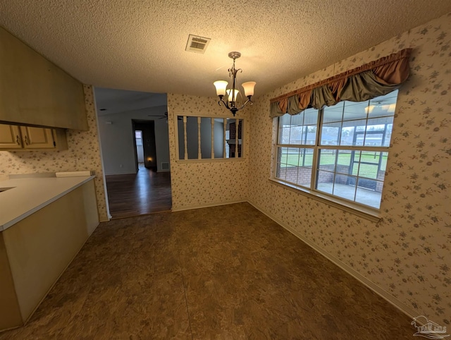 unfurnished dining area featuring dark hardwood / wood-style flooring, ceiling fan with notable chandelier, and a textured ceiling