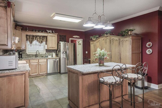 kitchen with light stone counters, hanging light fixtures, appliances with stainless steel finishes, a center island, and crown molding