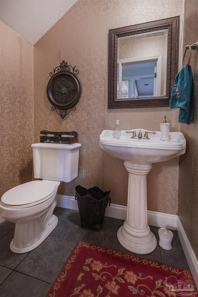 bathroom featuring tile patterned flooring, lofted ceiling, and toilet