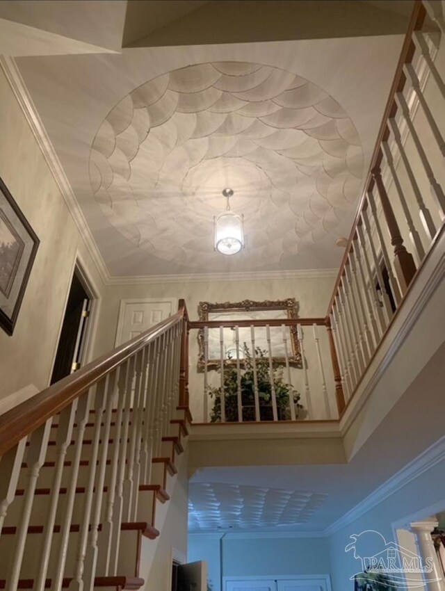 stairway featuring a notable chandelier, wood-type flooring, and crown molding