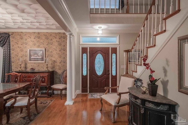 entryway featuring ornate columns, wood-type flooring, and crown molding