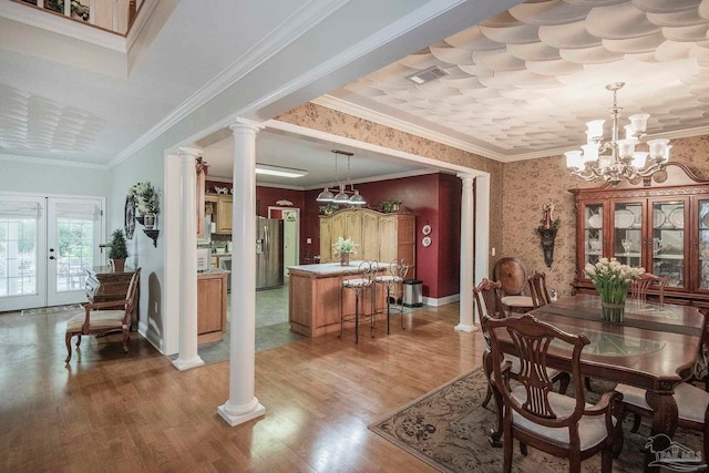 dining space featuring decorative columns, ornamental molding, hardwood / wood-style floors, and a notable chandelier