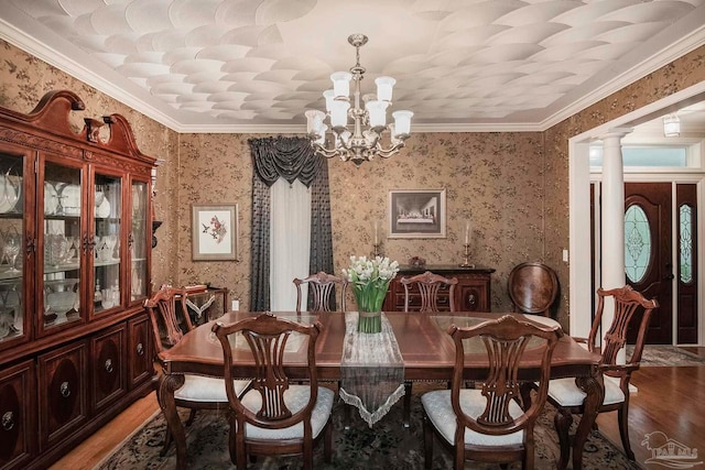 dining room featuring ornate columns, crown molding, a chandelier, and hardwood / wood-style flooring