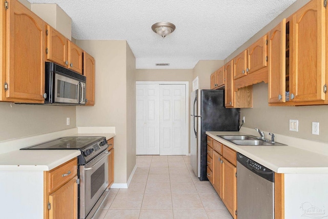 kitchen featuring stainless steel appliances, a textured ceiling, sink, and light tile patterned floors