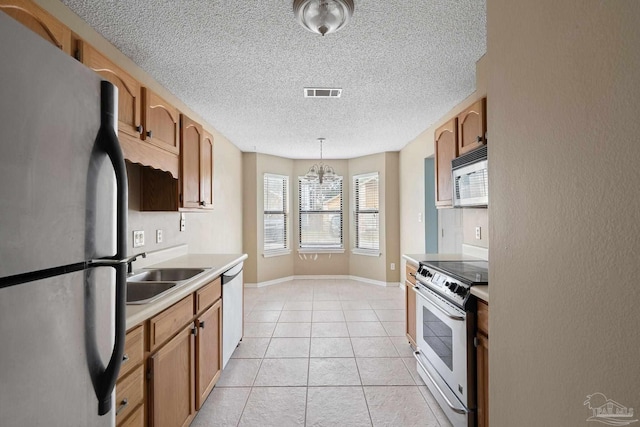 kitchen featuring decorative light fixtures, a notable chandelier, light tile patterned floors, appliances with stainless steel finishes, and sink