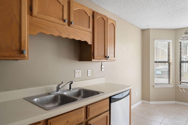 kitchen with stainless steel dishwasher, light tile patterned flooring, a textured ceiling, and sink