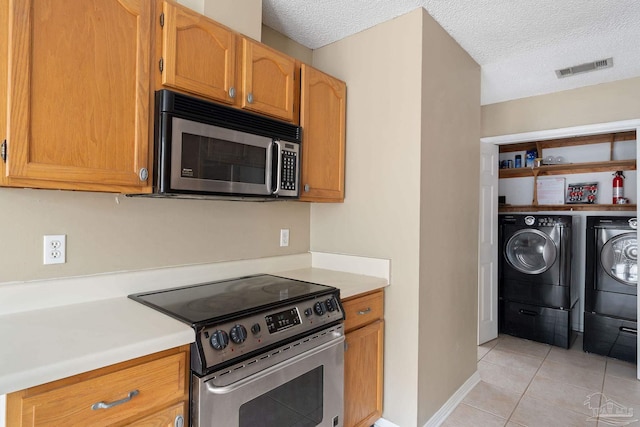 kitchen featuring stainless steel appliances, a textured ceiling, light tile patterned floors, and independent washer and dryer