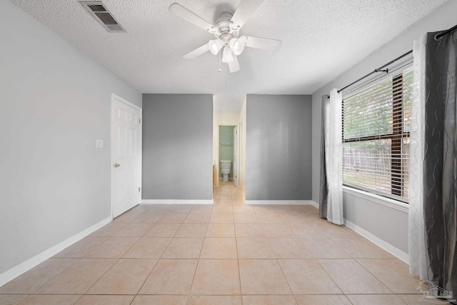 tiled empty room featuring a textured ceiling, ceiling fan, and plenty of natural light