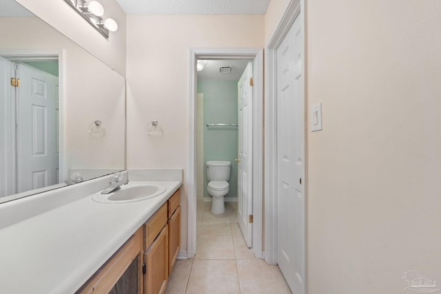 bathroom featuring a textured ceiling, vanity, tile patterned floors, and toilet