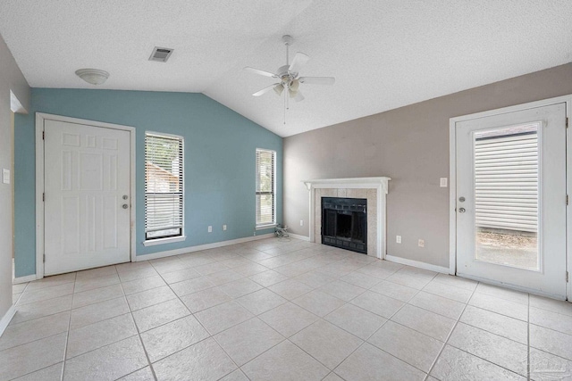 unfurnished living room featuring a textured ceiling, a fireplace, lofted ceiling, ceiling fan, and light tile patterned floors