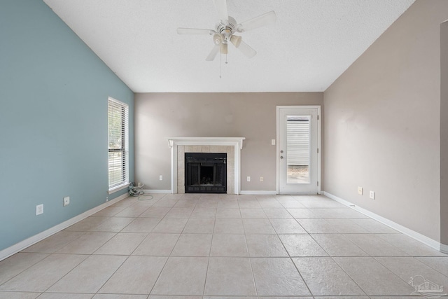 unfurnished living room with ceiling fan, lofted ceiling, a fireplace, and light tile patterned floors