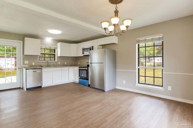 kitchen featuring appliances with stainless steel finishes, light wood-type flooring, a chandelier, and a sink